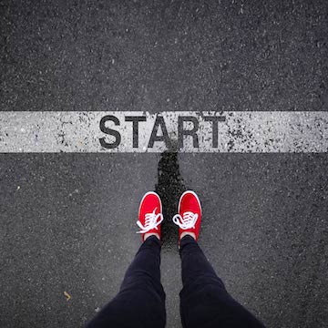 Image of feet wearing red shoes standing at a line on the ground that says Start.